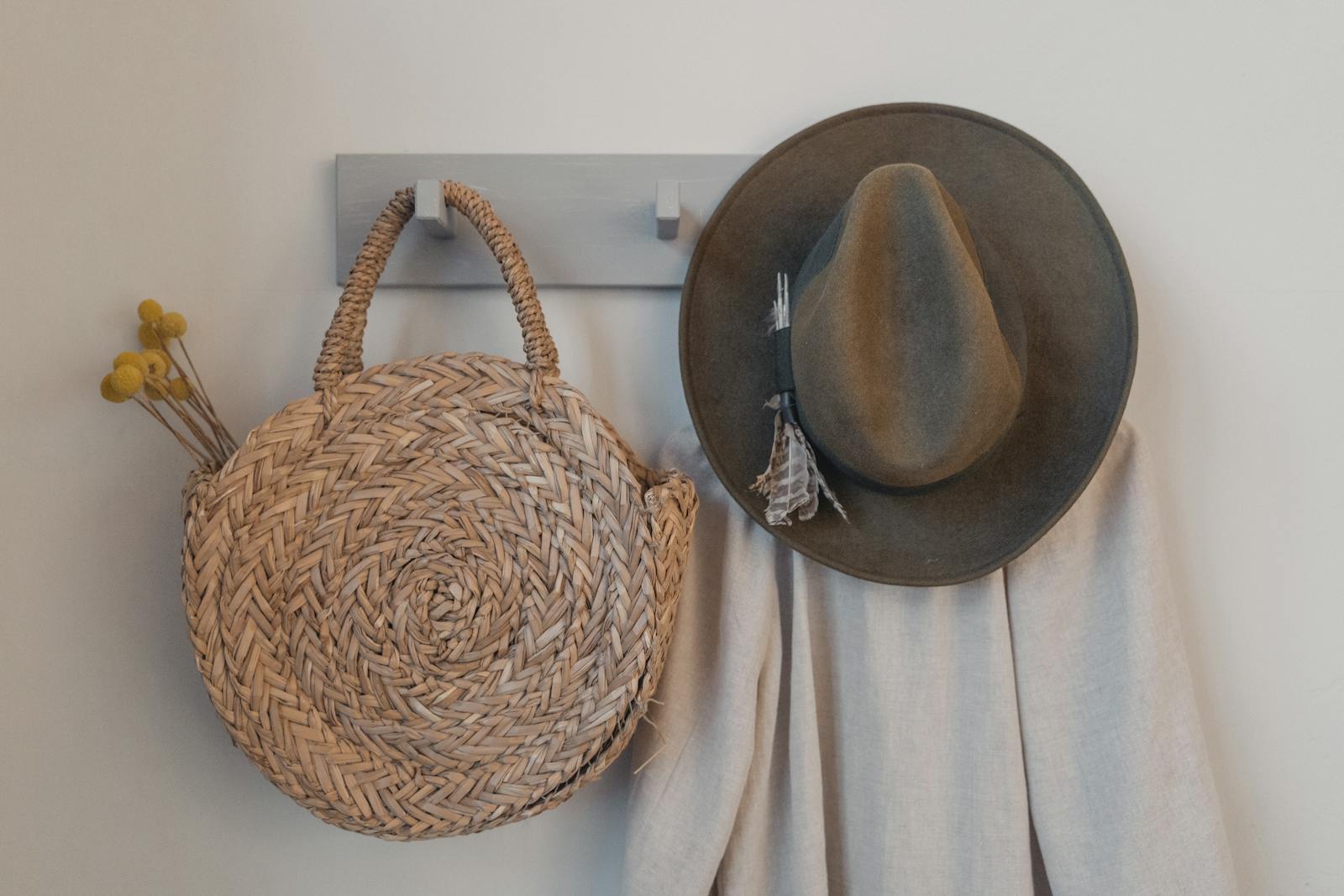 A rustic woven bag and hat hanging on a peg, showcasing minimalist interior decor.